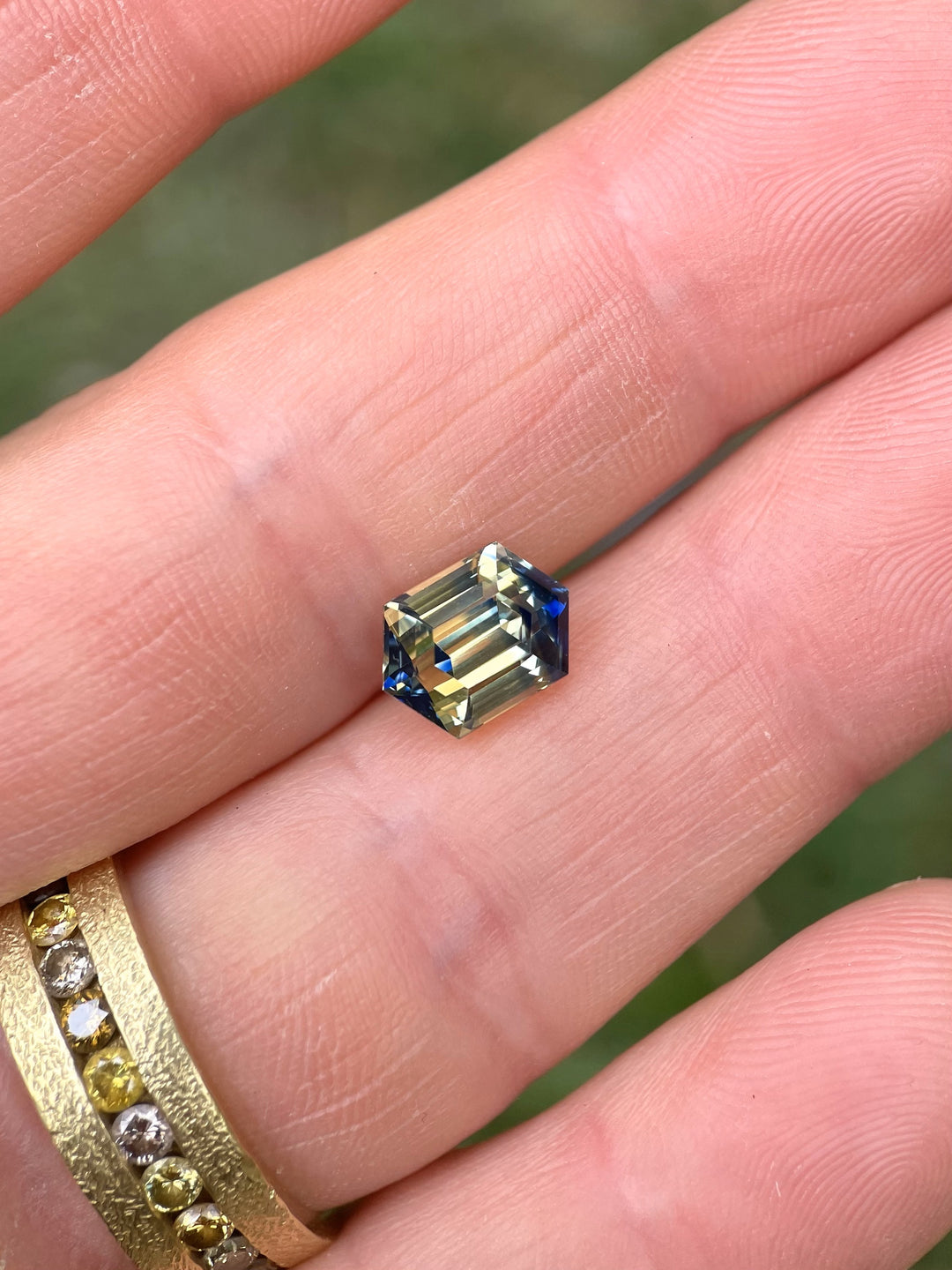 Macro view of a 4.13ct untreated sapphire with striking yellow and blue hues, precision-cut into a hexagonal step shape.