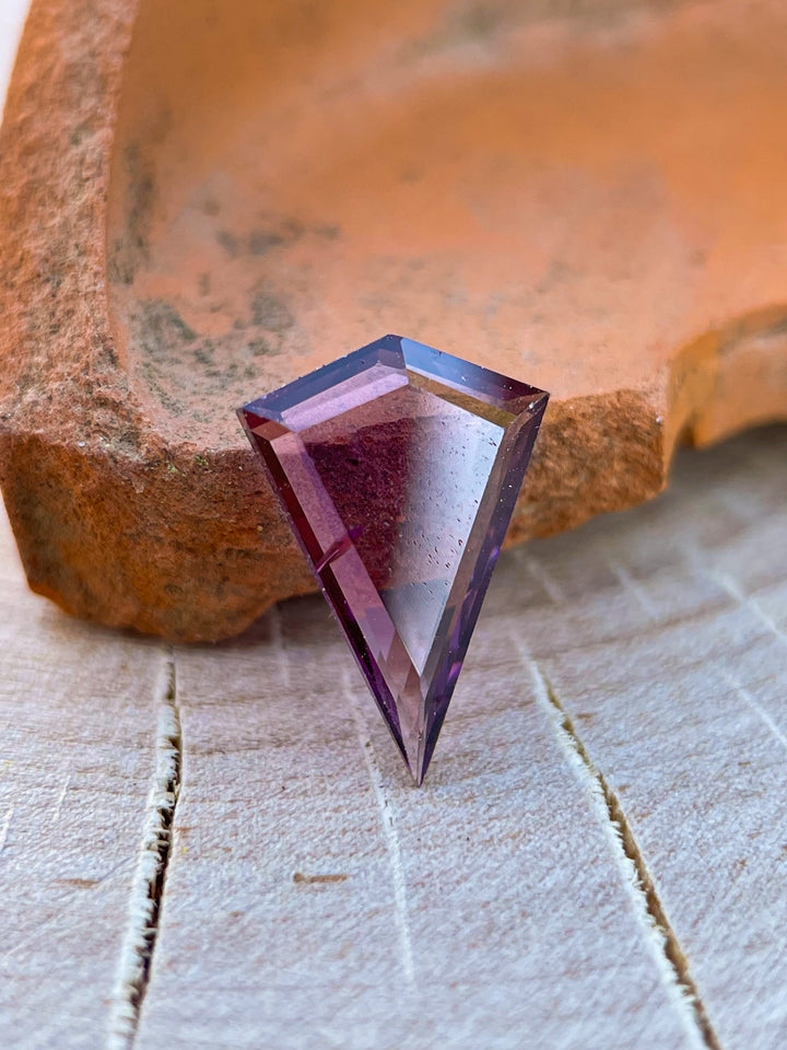 Detailed view of a 1.44 carat spinel gemstone in a custom kite portrait cut, with purple-pink hues and untreated clarity, sourced from Sri Lanka.