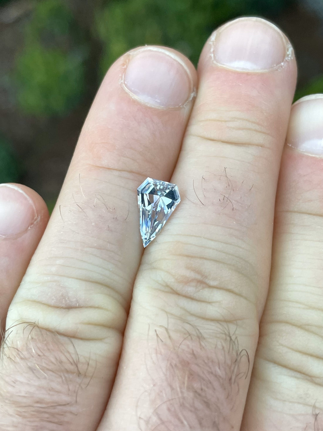 A 1.50-carat shield-shaped sapphire with a step cut, showcasing elegant gray, blue, and yellow tones. Untreated and ethically sourced from Sri Lanka, this gemstone is a striking piece.