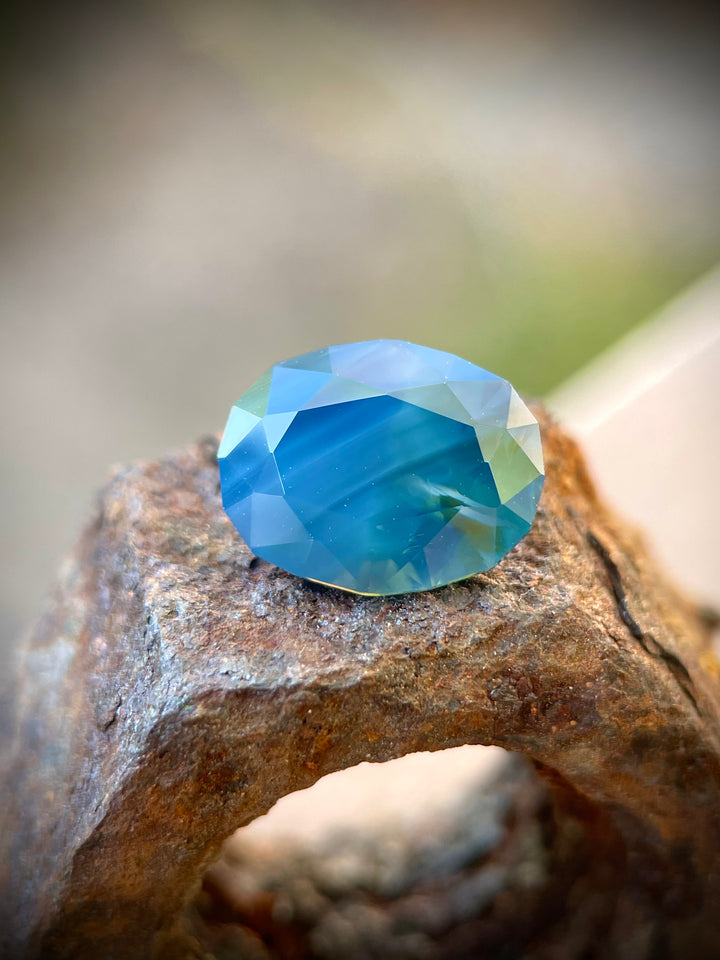 5.23 carat blueberry, green, and teal sapphire, oval cut, measuring 12.07 x 9.53 x 6.12 mm, untreated and sourced from Gombe, Nigeria, priced at $6276.