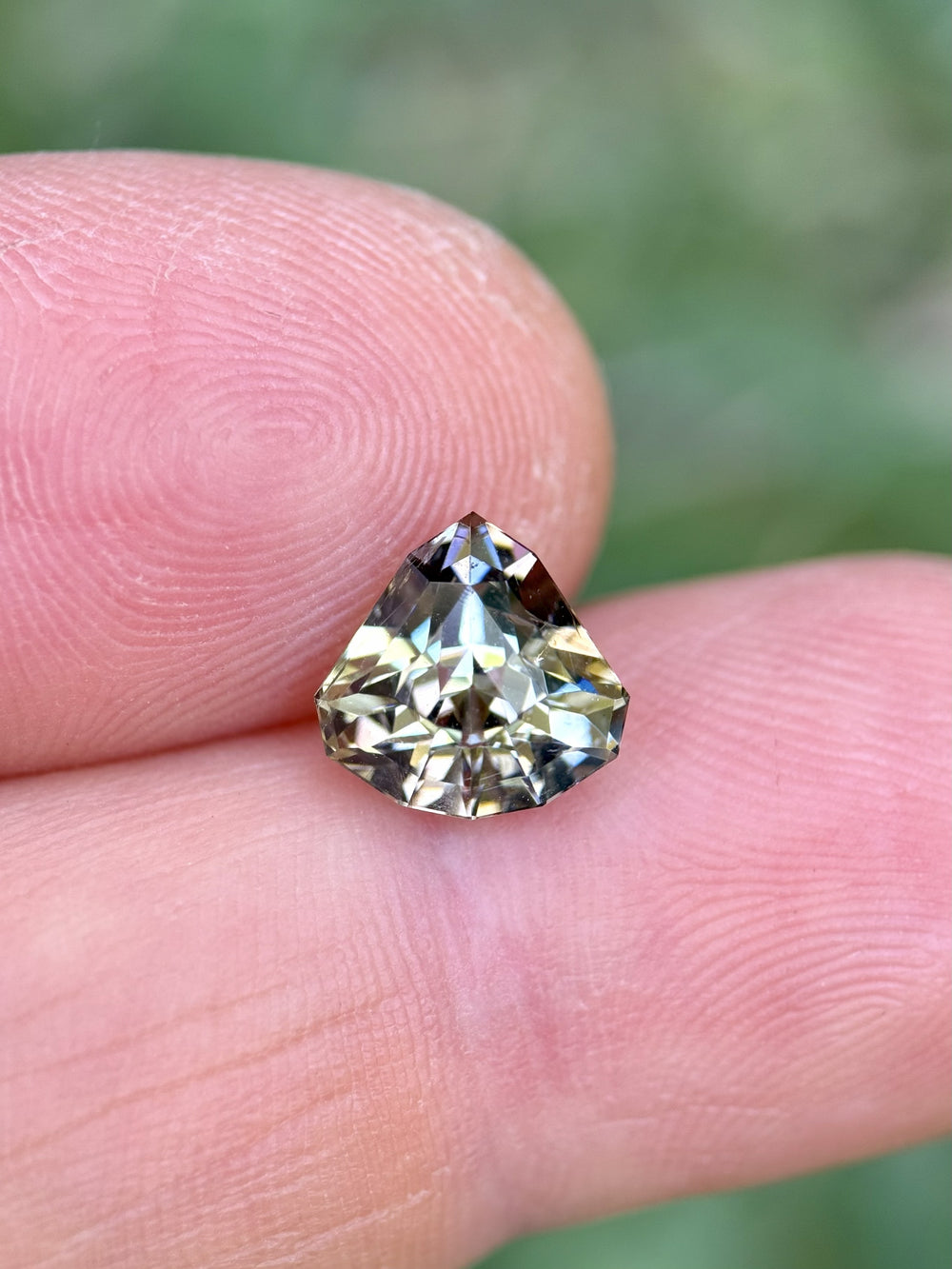 2.87 carat Tanzanite gemstone with yellow, lavender, and teal tones held on fingertip – custom shield mixed cut, untreated
