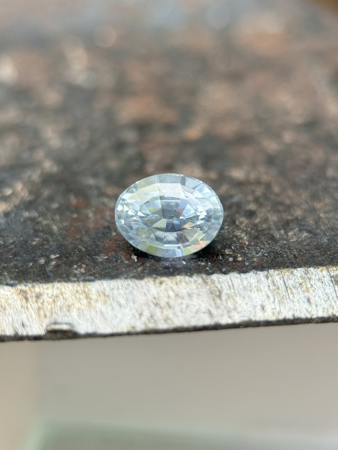 1.00ct Montana sapphire in teal and cornflower hues resting on fingertip, oval mix cut