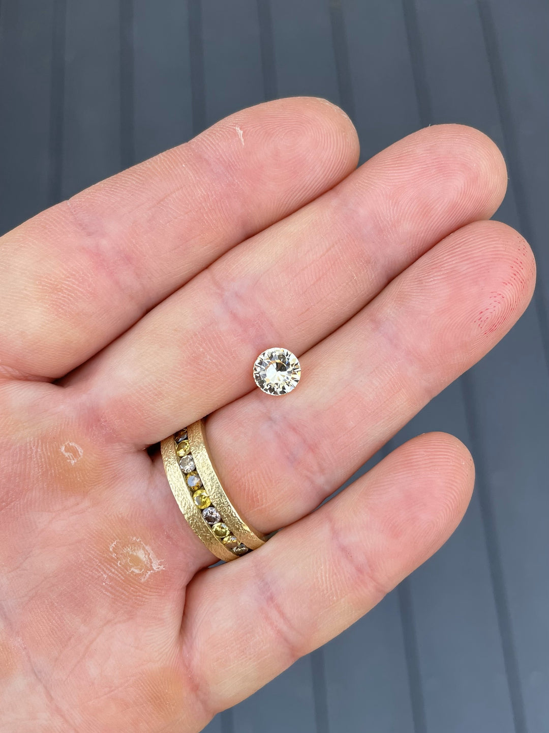 A 1.59-carat round brilliant peach yellow sapphire resting on a hand, highlighting its vivid brilliance and natural color under daylight.