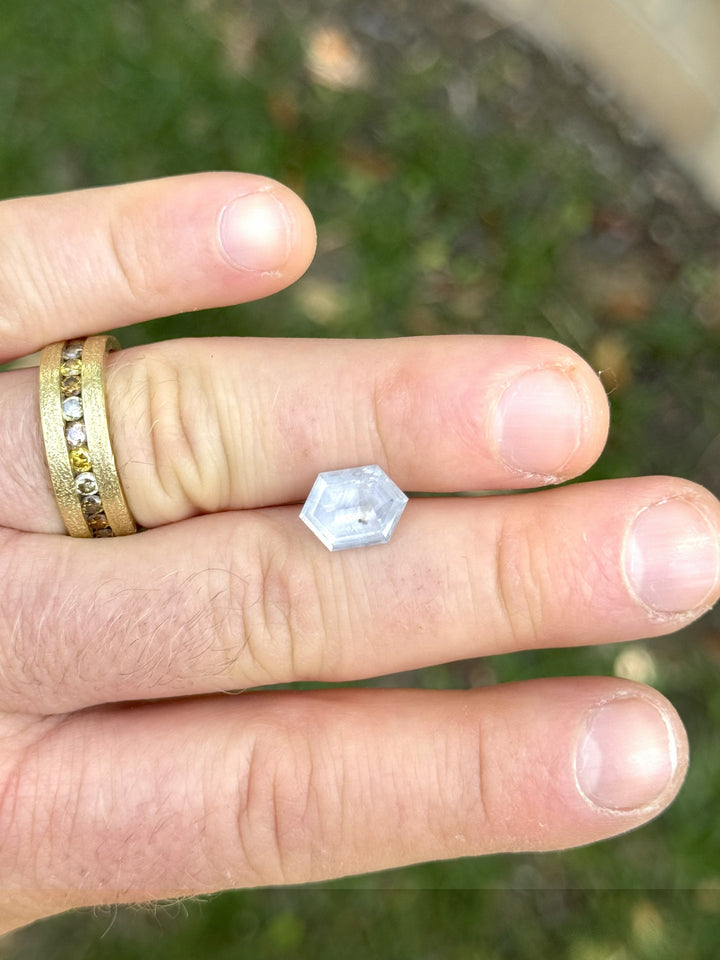 Large 4.34 carat Montana sapphire resting on hand, highlighting hexagonal cut and soft color shift between blue and lavender tones