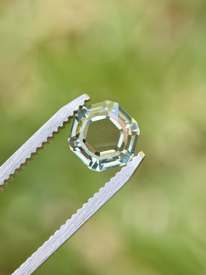 Close-up of a 2.09ct light teal Montana sapphire on fingertip, custom portrait hexagon cut, unheated.