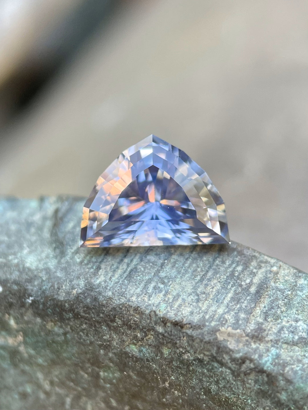 Close-up of a 1.66-carat sapphire resting on a textured surface, revealing its stunning periwinkle and lavender hues.