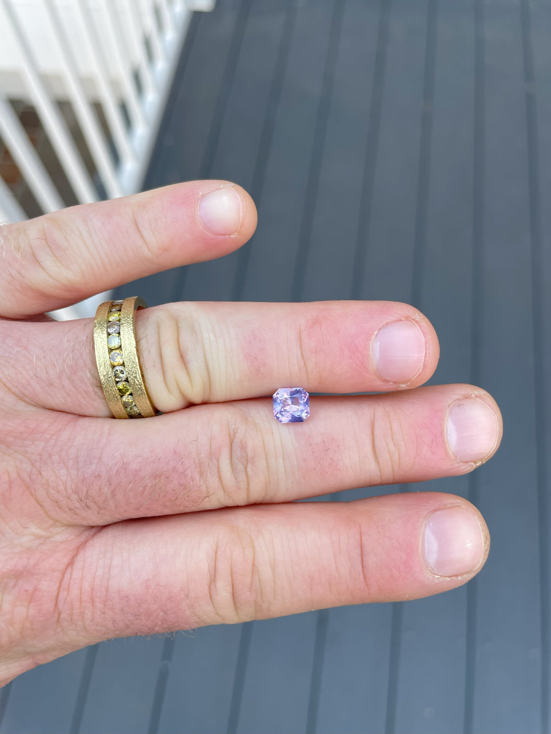 1.57 carat Sri Lankan sapphire displayed on a textured cinnamon stick, highlighting its custom radiant cut and opalescent beauty.