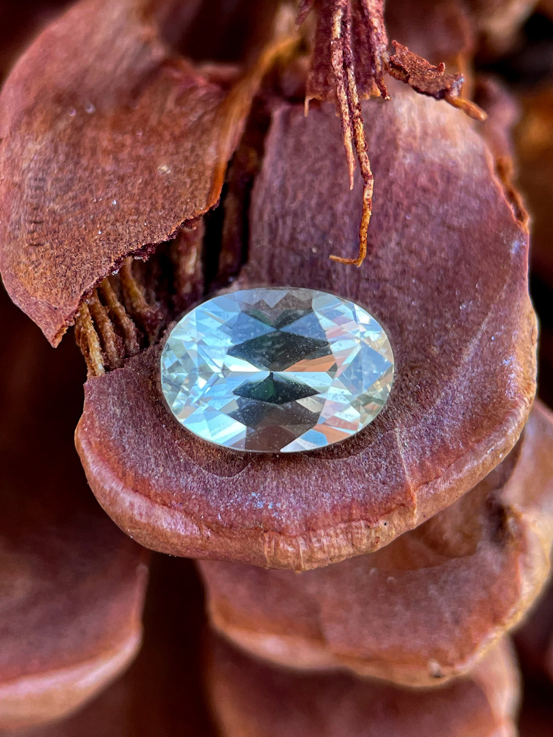 A stunning 2.05-carat oval sapphire, featuring a natural blend of gray and yellow tones, elegantly placed on a rich brown textured surface.