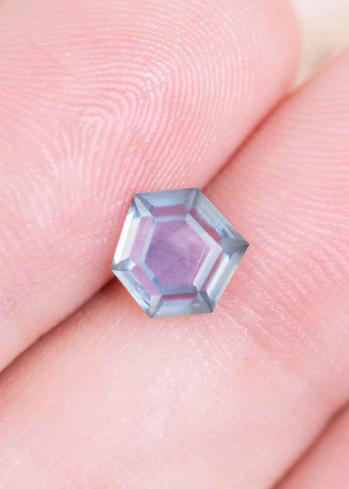 1.37 carat teal blue seafoam Montana sapphire resting on fingertips to show scale, featuring a geometric hexagonal step cut with sharp facet definition and natural untreated color.