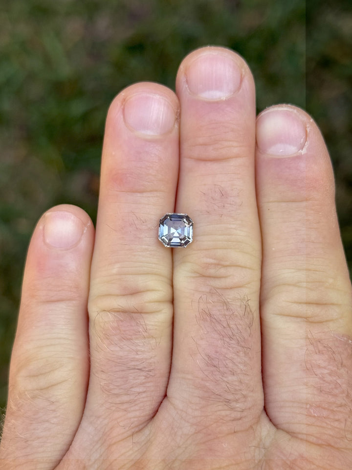 Hand scale view of untreated 1.99ct Tanzanite with Asscher cut showing opalescent green, blue, and pastel colors