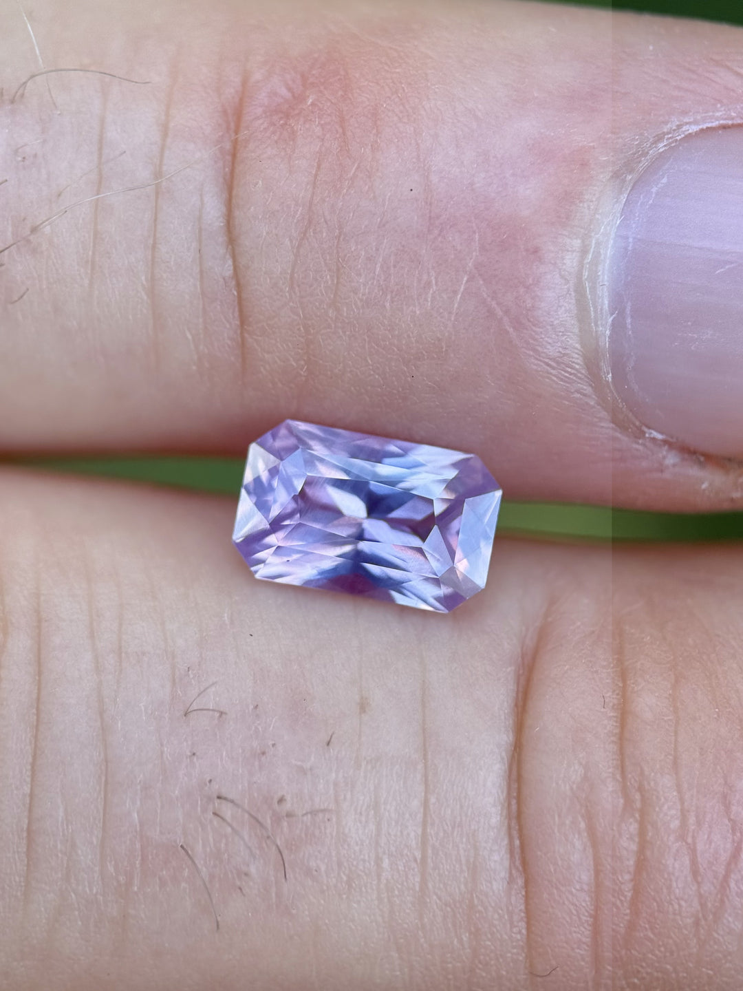 Lavender and pink 2.00 carat radiant sapphire resting on a hand for scale – unheated Sri Lankan gem