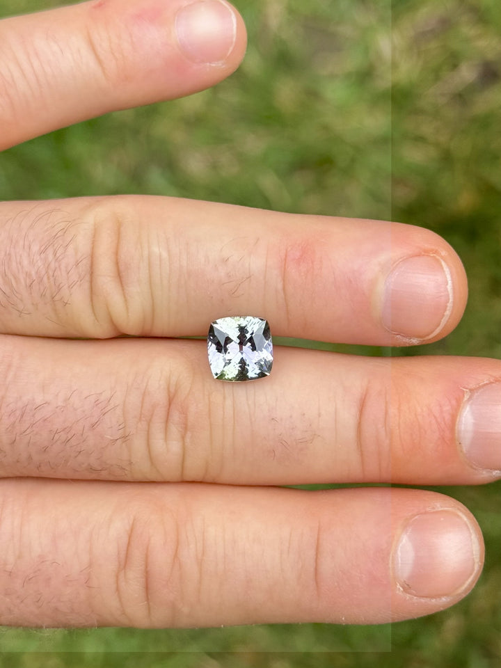 Bi-color Tanzanite gem with green and purple hues shown on hand – 3.13ct cushion cut stone for custom fine jewelry