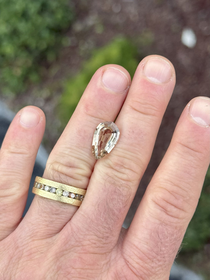 5.36CT champagne brown tourmaline displayed on a hand for scale, highlighting its geometric pear shape and step cut symmetry under daylight, no-treatment natural gemstone from Congo, Africa.