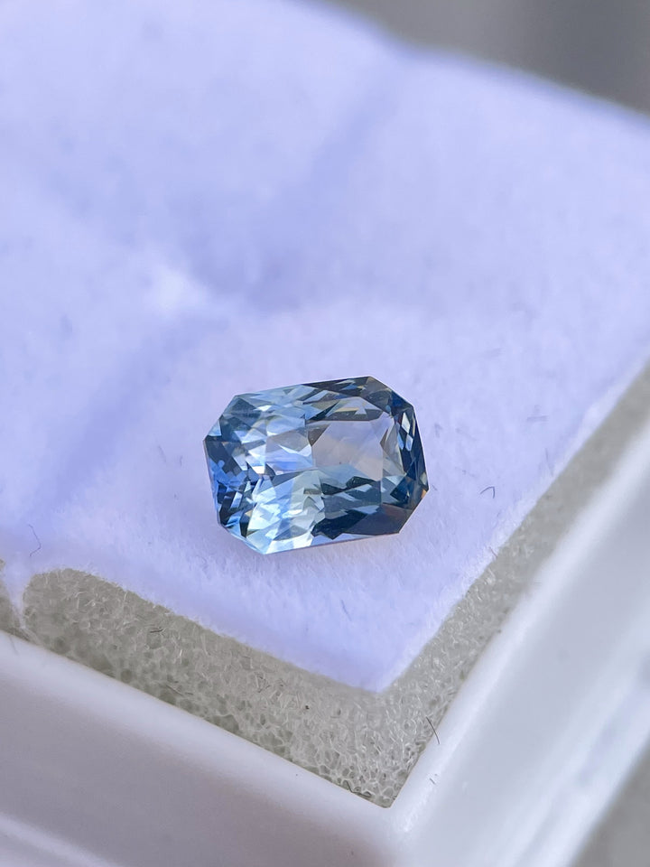 A radiant-cut parti sapphire weighing 1.52 carats, captured in natural lighting. The gemstone features unique blue, yellow, teal, and green tones and is ethically sourced from Sri Lanka with no treatments applied.
