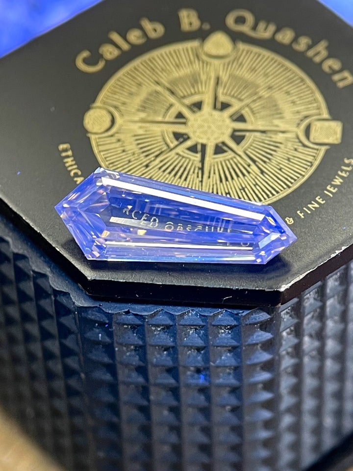 Close-up of a 2.02-carat champagne diamond with an elongated shield step cut, resting on a black presentation box with gold detailing.