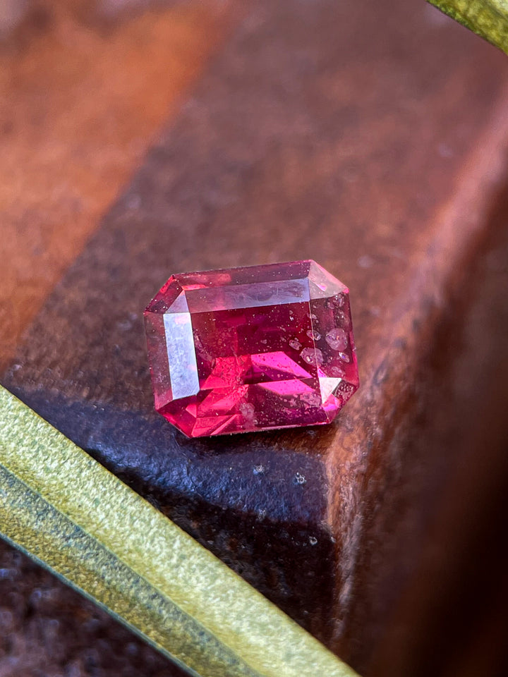 Close-up of a 1.36 carat Kenyan garnet gemstone, featuring a vibrant red-pink hue, octagonal step cut design, and natural untreated clarity.
