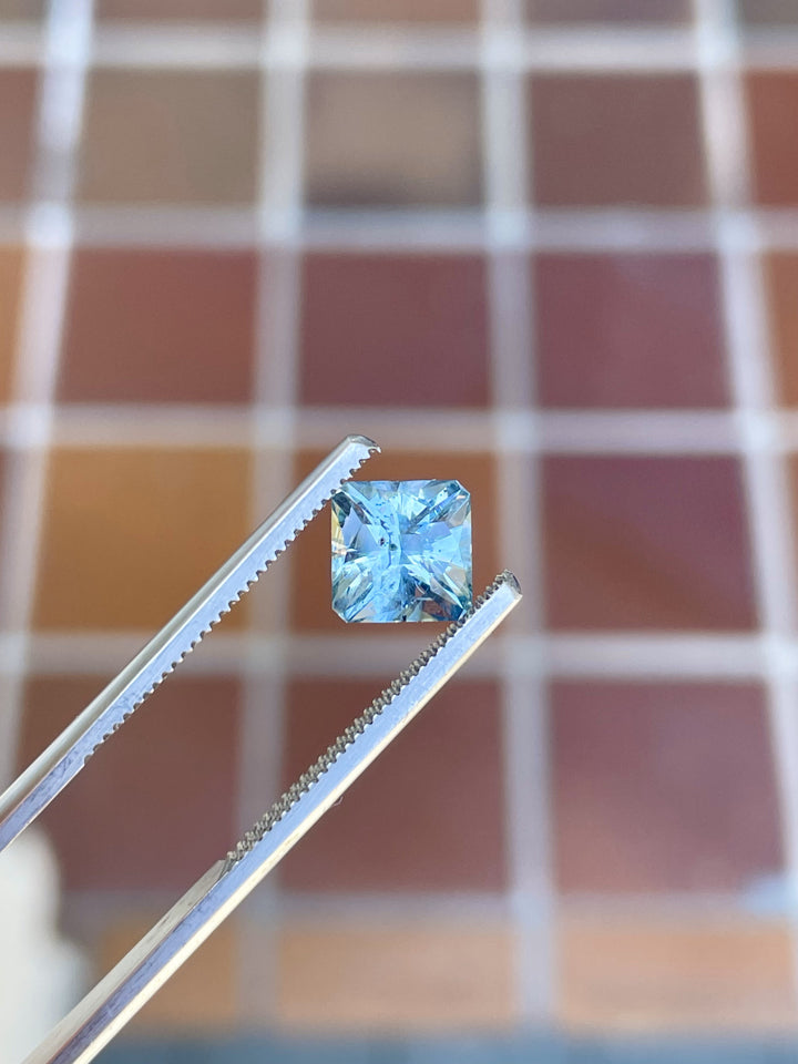 Stunning No Heat Sapphire in Teal and Blue hues, precision cut in a Cushion shape, weighing 2.49 carats, displayed against a tiled background. Originating from El Dorado Bar Deposit, Montana, USA.