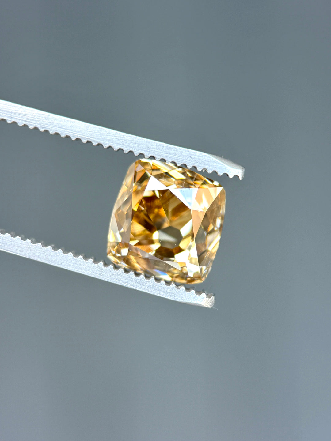 Natural Canadian champagne diamond displaying broad antique cushion facets with warm bronze and deep champagne reflections across the crown.