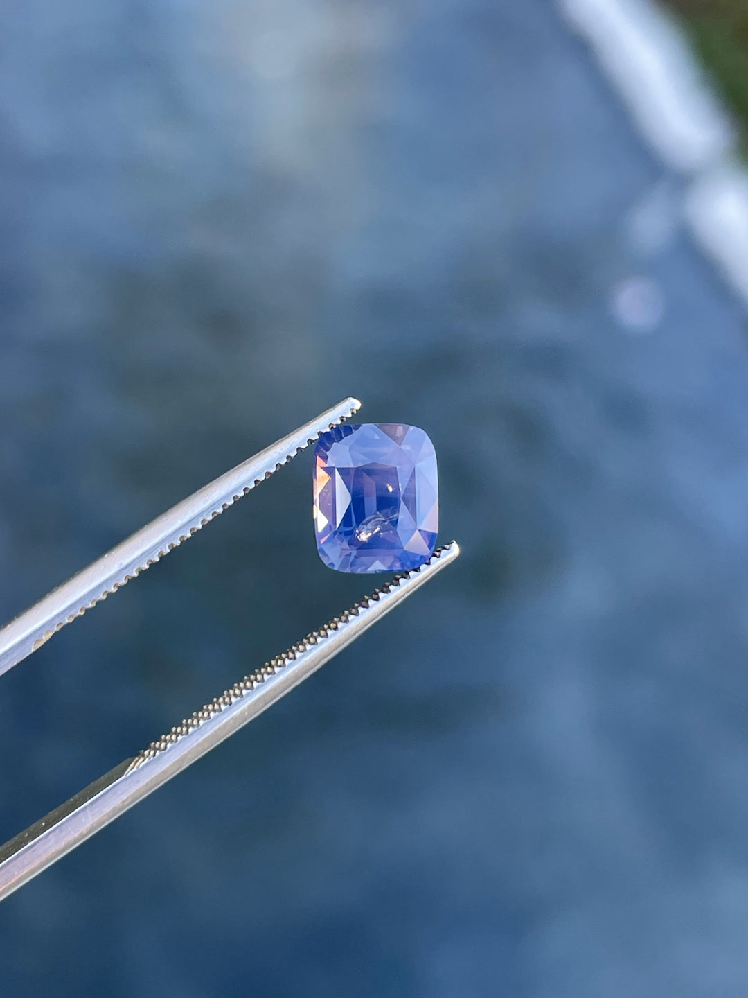 Close-up of a natural cushion-cut sapphire weighing 2.56 carats, showcasing its mauve, pink, and purple opalescent tones.