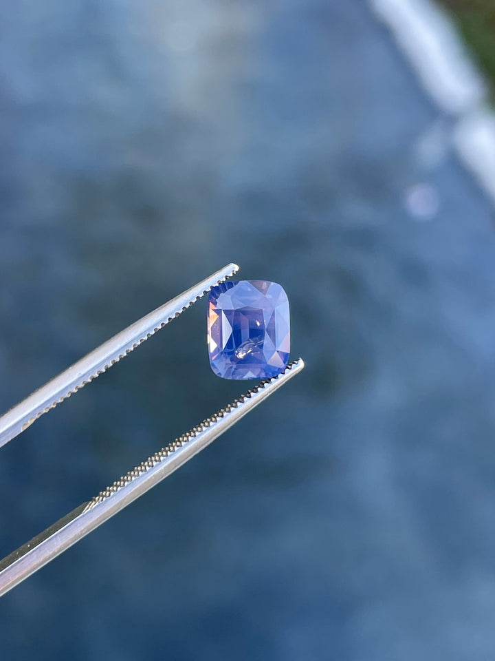 Close-up of a natural cushion-cut sapphire weighing 2.56 carats, showcasing its mauve, pink, and purple opalescent tones.