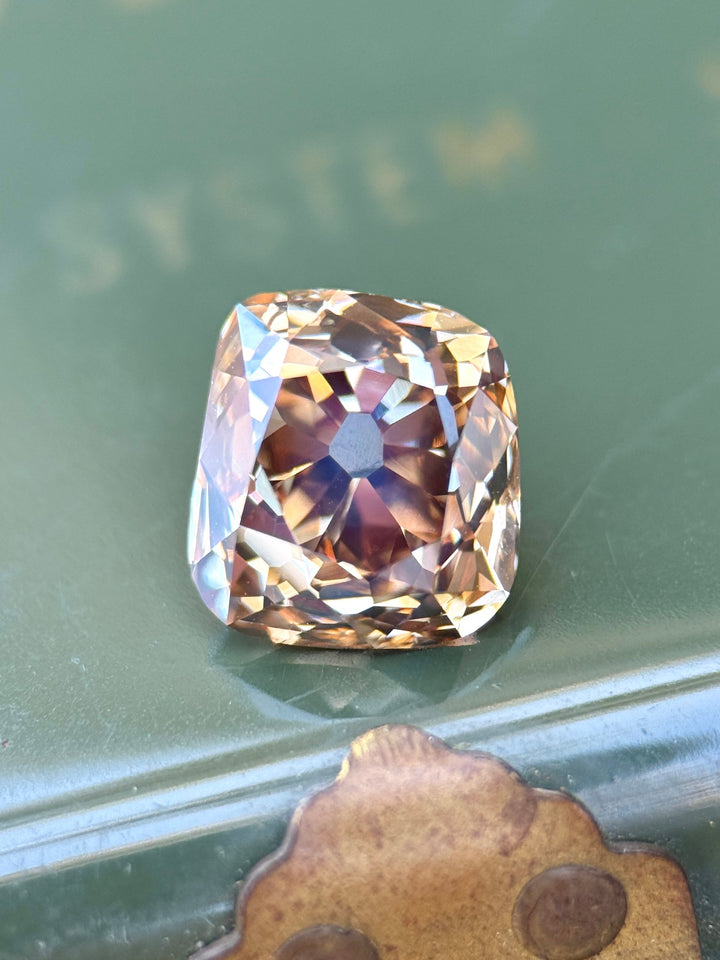 3.93 carat Fancy Deep Brown Champagne Diamond resting on green pill box, displaying antique old mine cushion faceting, warm cognac flashes, and VVS1 clarity from Canada's Ekati Diamond Mine.