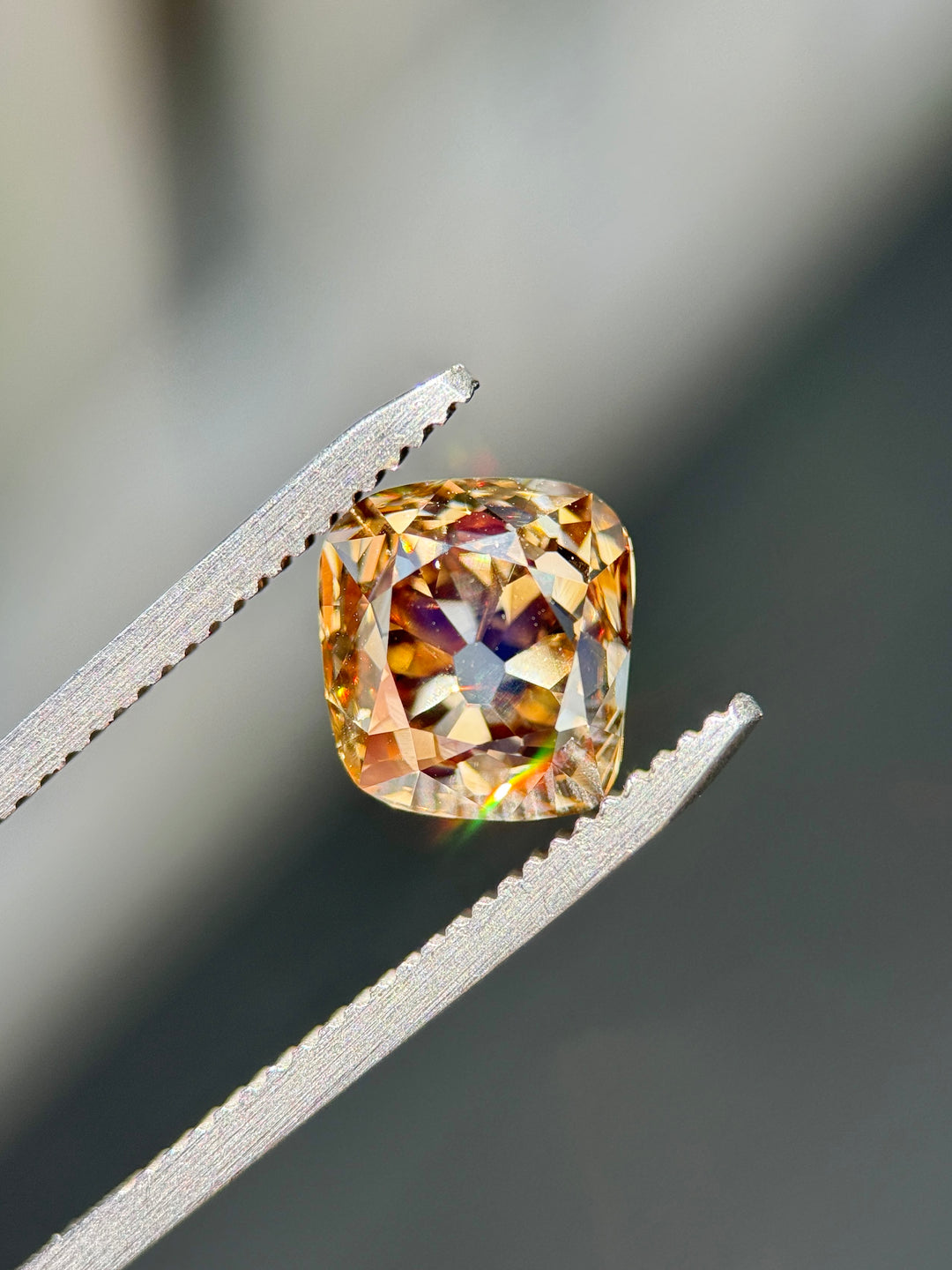 Natural 3.93ct Fancy Brown Champagne Diamond held in gem tweezers, showing antique old mine cushion cut proportions, deep champagne body color, and broad vintage facet reflections.