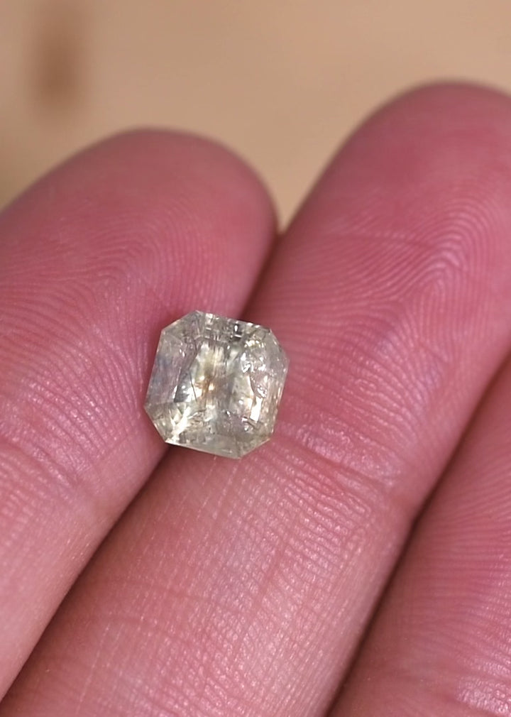Macro video of a natural Montana sapphire Asscher cut under shifting light, demonstrating seafoam and teal color play, internal crystal structure, and the depth of an unheated 2.25 carat sapphire.
