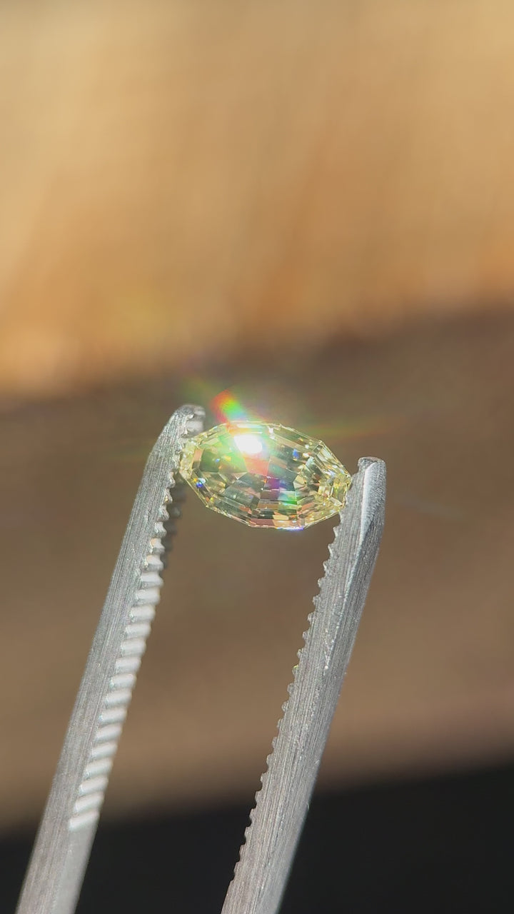 Handheld video of a 0.99 carat light yellow VVS1 diamond from Gahcho Kué, Canada, gently moved in tweezers to reveal the brilliance and intricate symmetry of its antique moval step cut under natural light.