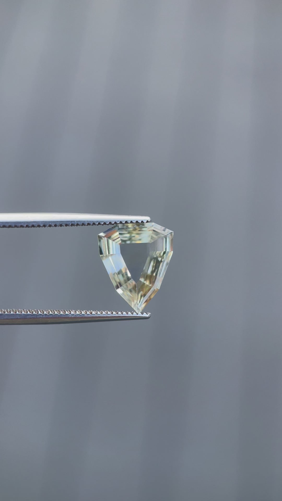 A rotating 2.47-carat yellow-green sapphire with a modified geometric step cut. The video showcases the precision of the portrait shield shape as the light interacts with its facets. The untreated sapphire from Sri Lanka measures 11.68mm by 9.62mm by 2.63mm.