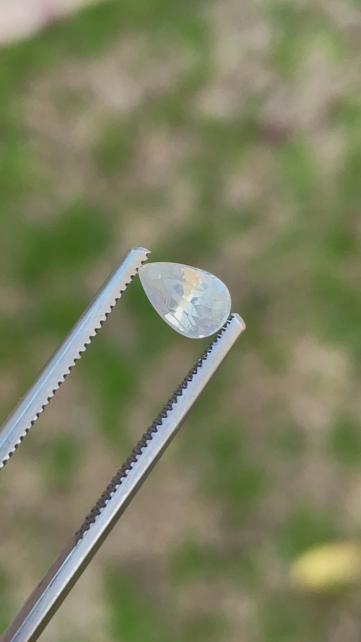 1.05-carat unheated Sri Lankan yellow sapphire being held in tweezers, capturing its brilliance under changing angles.