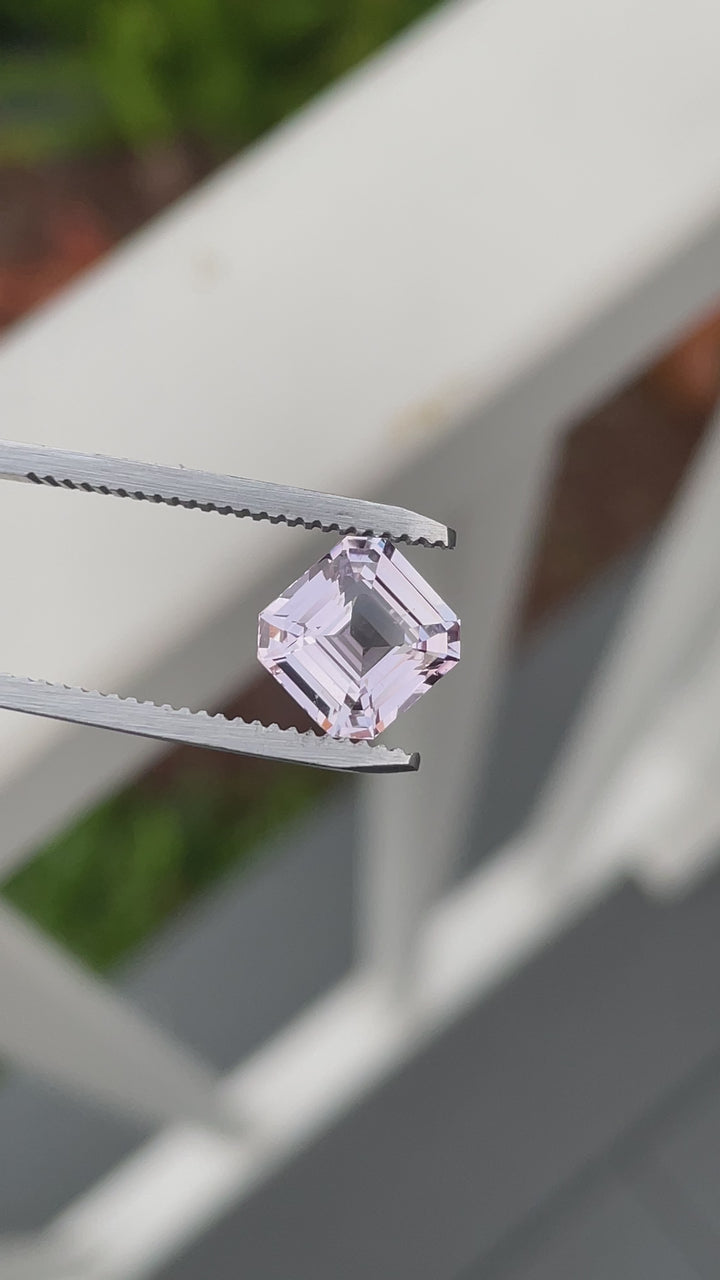 Video of a 3.02 carat sapphire in custom emerald cut showing vivid lavender-pink colors and crisp step facets from multiple angles on a blue textured backdrop.