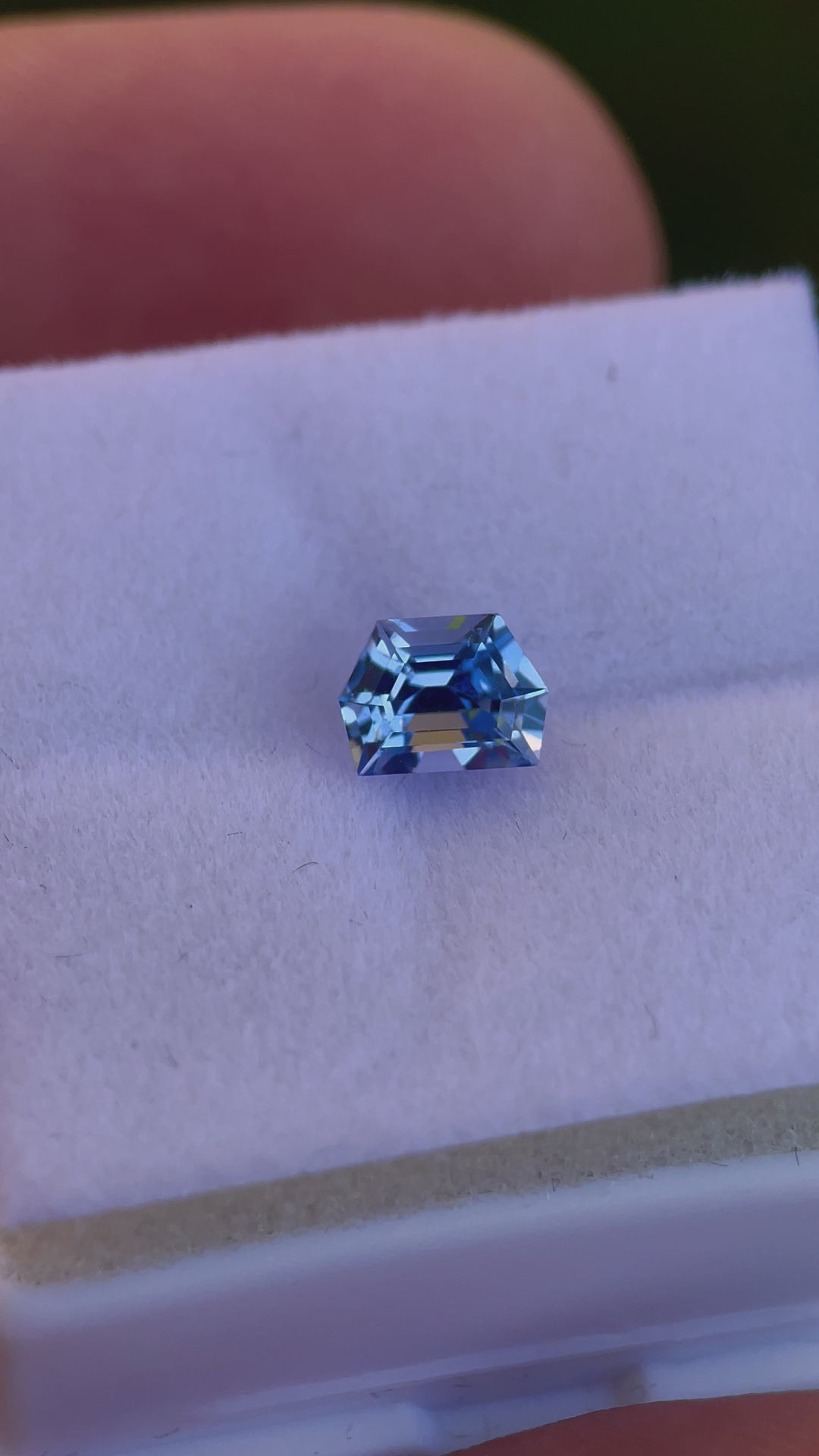 Close-up video of a 1.42 carat No Heat Sapphire, emphasizing its geometric step cut and rich cornflower blue color. The video captures the gemstone's internal fire and the play of light, presenting its flawless craftsmanship and natural beauty.
