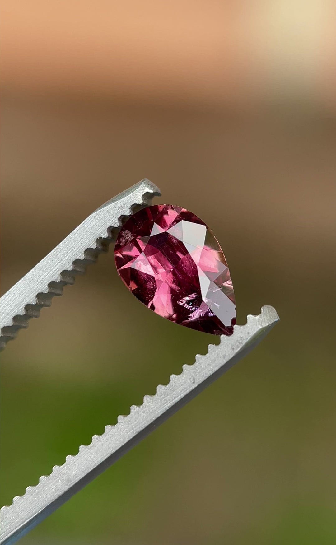  Rotating video of a 0.88 carat blush red sapphire from Umba River, capturing its natural brilliance and modified pear cut sparkle under natural light.