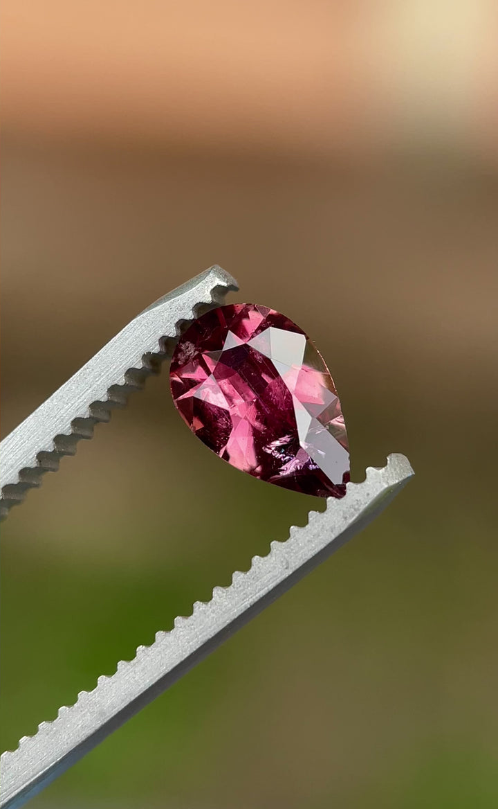  Rotating video of a 0.88 carat blush red sapphire from Umba River, capturing its natural brilliance and modified pear cut sparkle under natural light.
