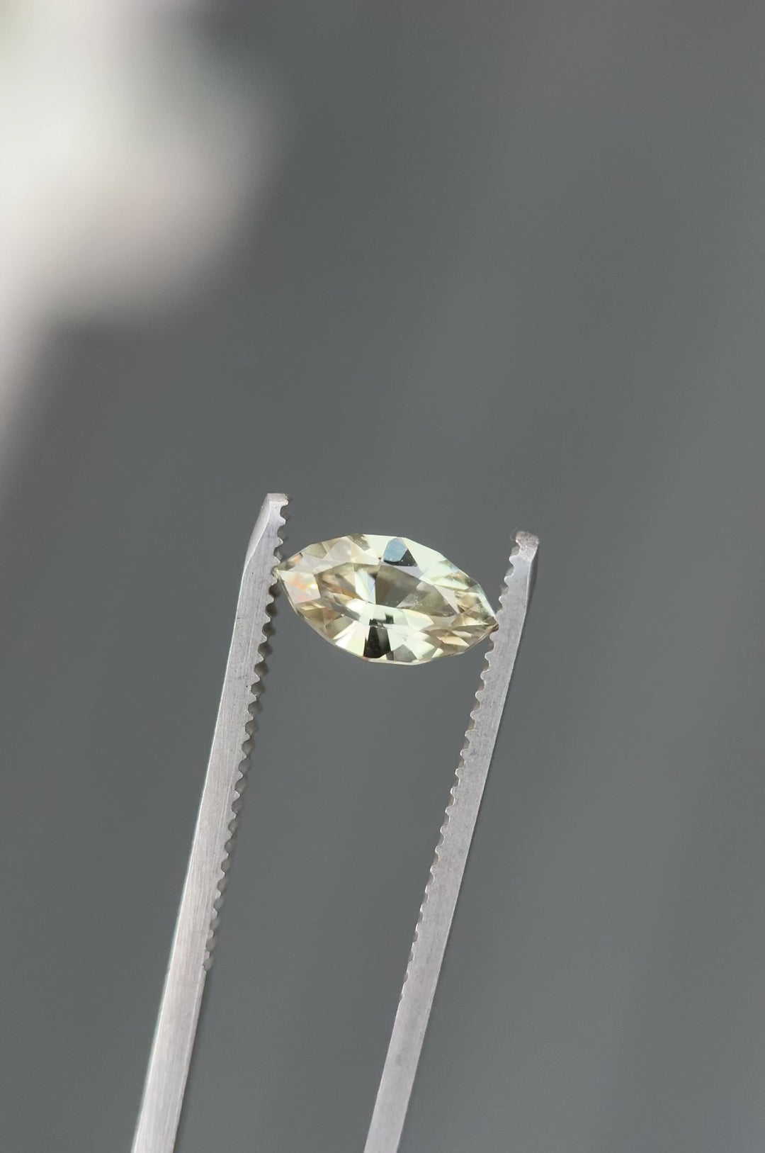 Close-up video of 1.61CT yellow sapphire rotating in gemstone tweezers under natural light, capturing sparkle, golden color, and fine craftsmanship of the precision marquise mixed cut, unheated sapphire from Sakaraha, Madagascar.