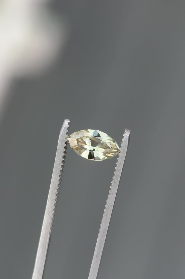 Close-up video of 1.61CT yellow sapphire rotating in gemstone tweezers under natural light, capturing sparkle, golden color, and fine craftsmanship of the precision marquise mixed cut, unheated sapphire from Sakaraha, Madagascar.