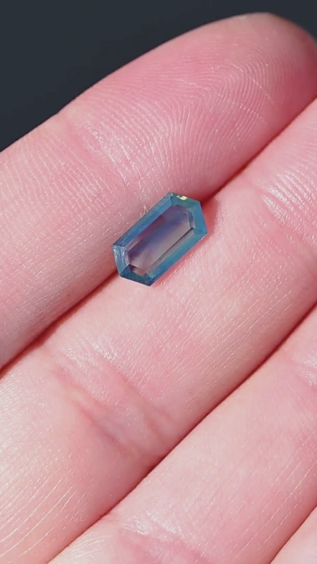 Discover a natural 1.55 carat opalescent teal blue sapphire from Gombe, Nigeria, presented on the hand for scale. Completely untreated, this elongated hexagonal portrait-cut gemstone features a softly translucent blue-green center framed by deeper teal facets. An elegant loose sapphire for bespoke engagement rings, contemporary pendants and custom fine jewelry.