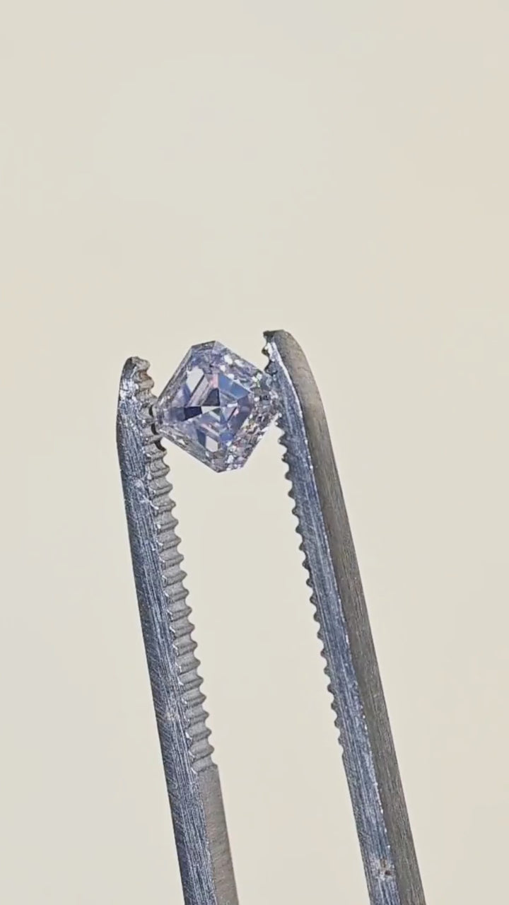 1.01 carat M color VVS1 Asscher cut diamond rotated in tweezers under sunlight, showing broad flashes of light across its concentric step facets.