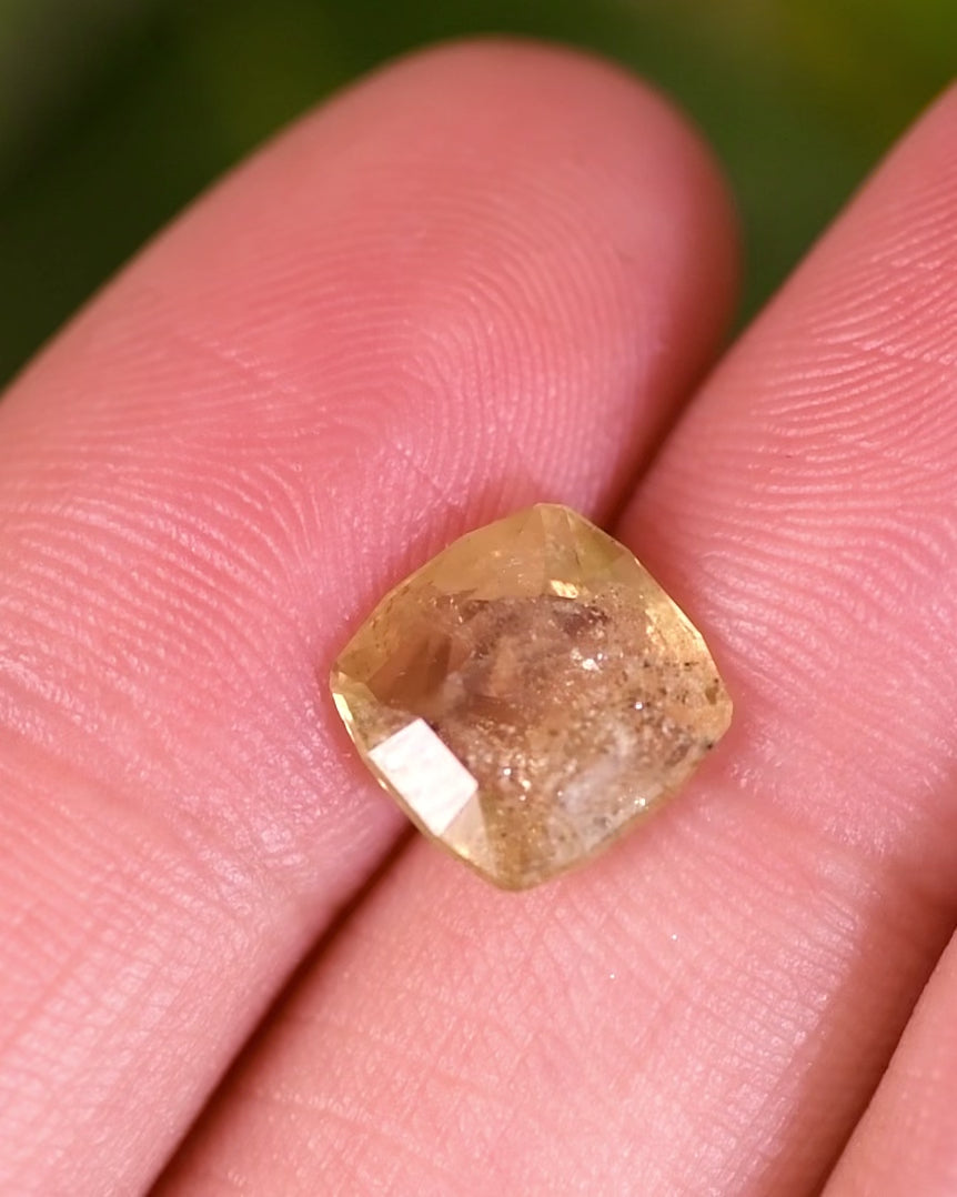 Macro video of 3.10 carat green yellow sapphire turning slowly, revealing natural sparkle and depth of its cushion cut facets, untreated sapphire from Umba River, Tanzania.