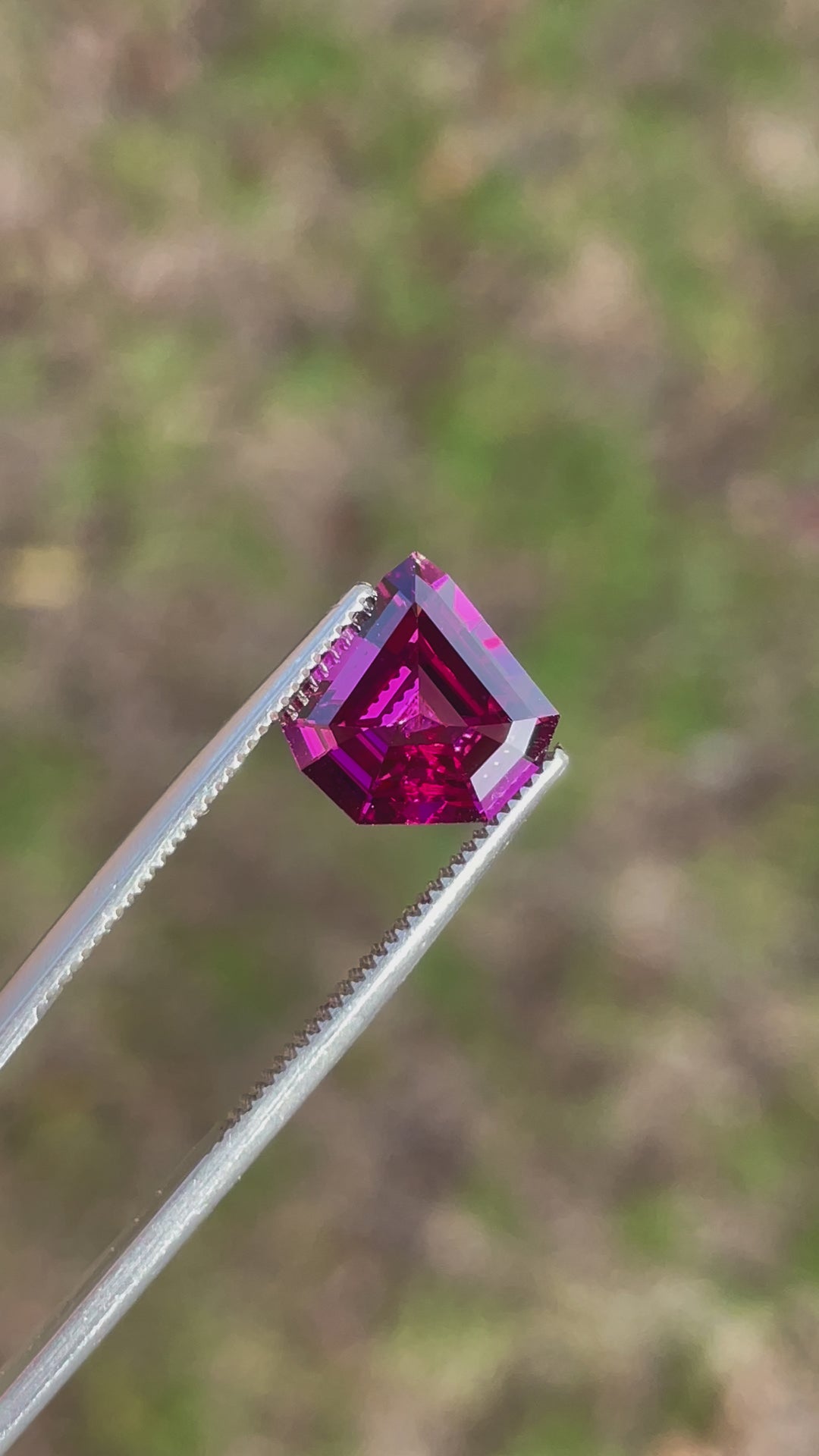 Video showcasing a 2.61 carat shield step cut garnet with a stunning play of purple, pink, and red hues, sourced from Mombo, Tanzania.