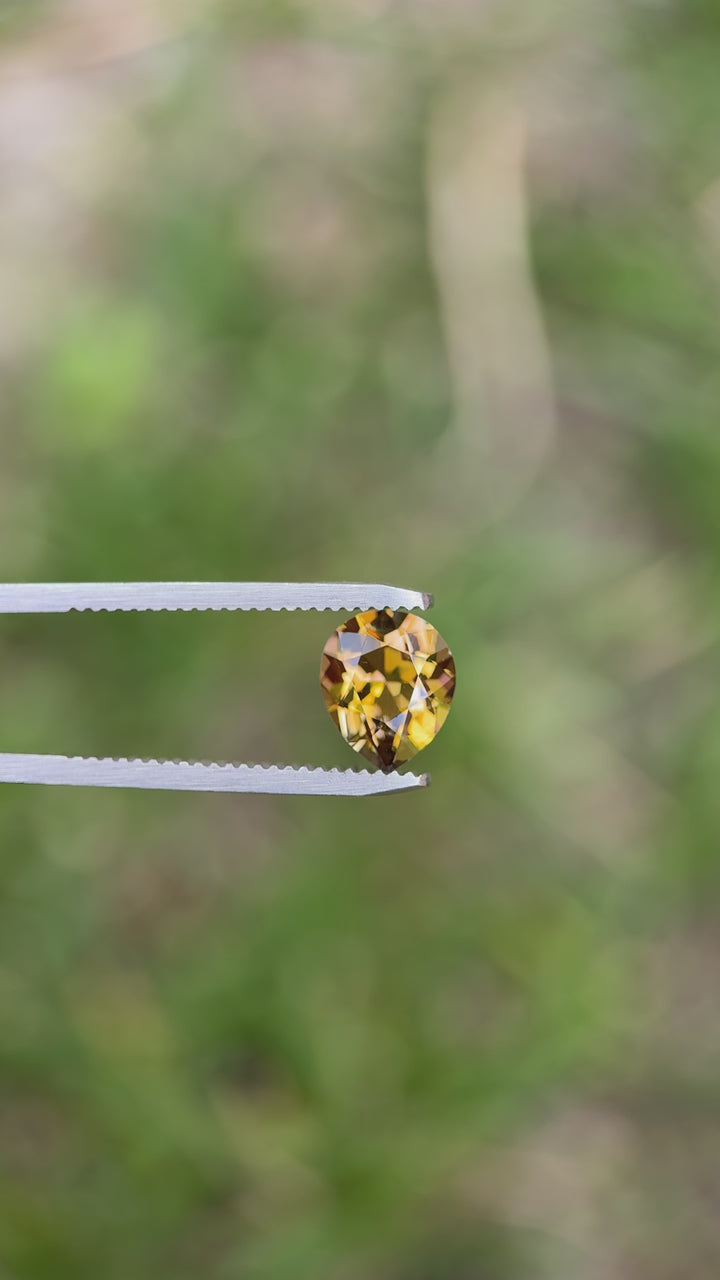 Rotating poval-cut 2.17 carat peach golden yellow tanzanite under natural light to highlight its clarity and brilliance