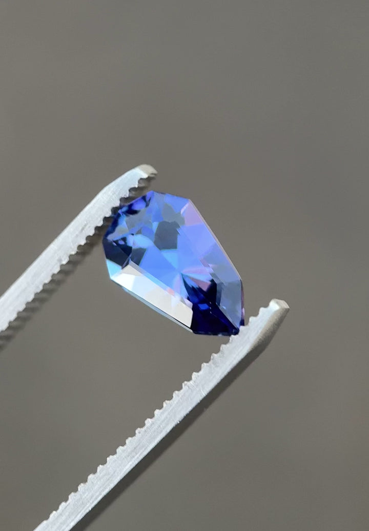 Rotating video of 2.42 carat custom elongated shield cut tanzanite showing its color shift between rich blue, purple, and mermaid green under natural lighting, unheated gem from Tanzania.