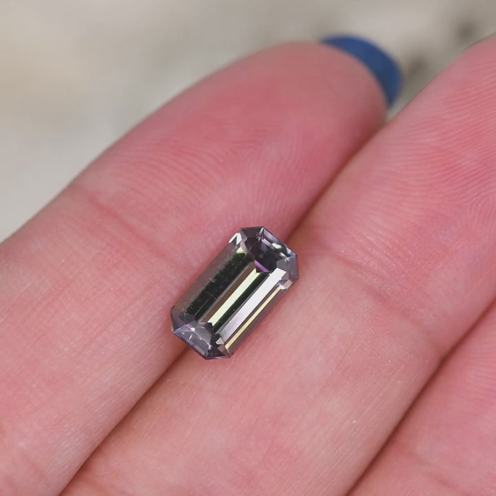 2.02 carat untreated purple green Tanzanite emerald cut rotating under natural light, Merelani Hills Tanzania gemstone showing step cut brilliance and natural color shift for custom jewelry