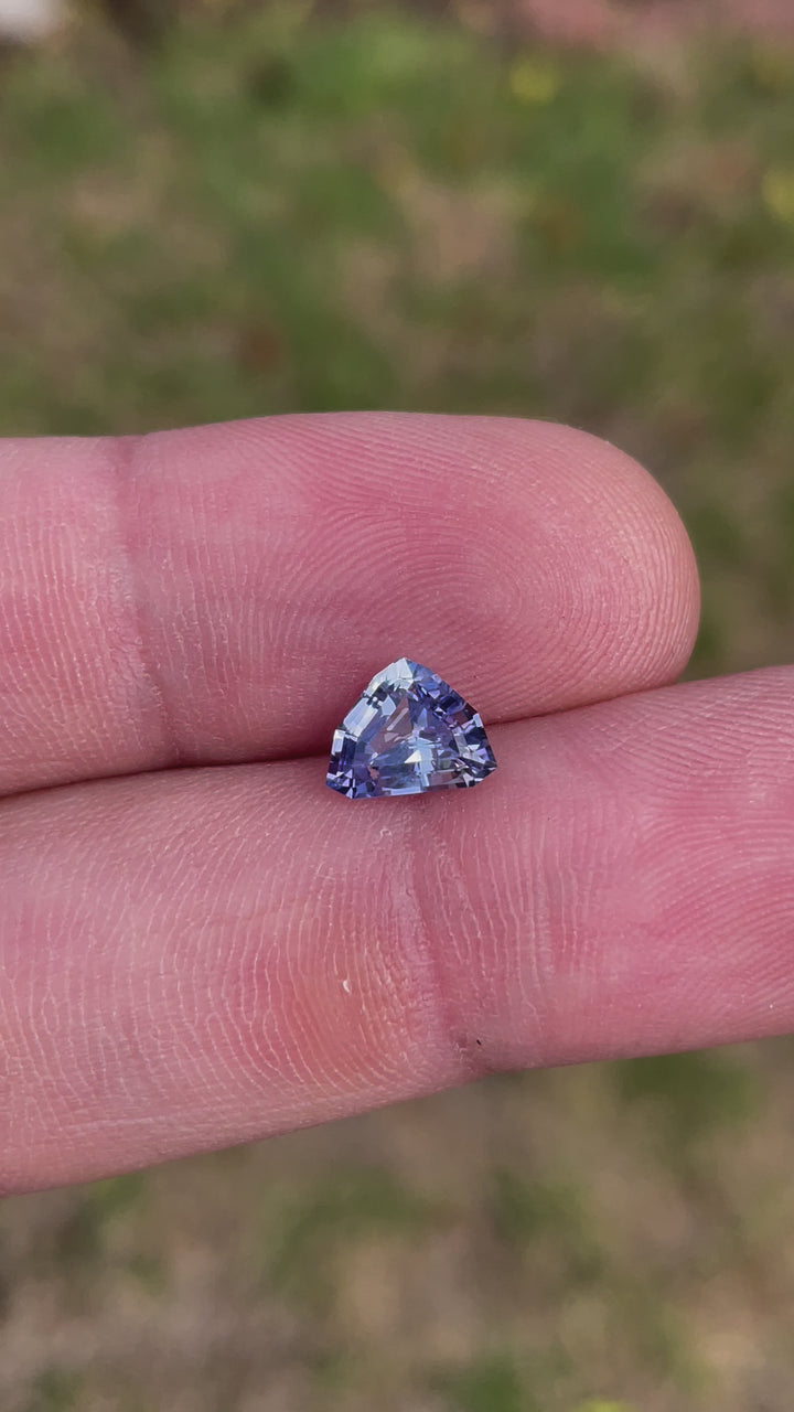A rotating 1.77-carat lavender and powder blue sapphire with a custom mix shield cut. The video captures the gem’s brilliance as it moves under natural light, showcasing its untreated nature and precision facets. The stone measures 6.99mm by 8.73mm by 4.03mm, originating from Sri Lanka.