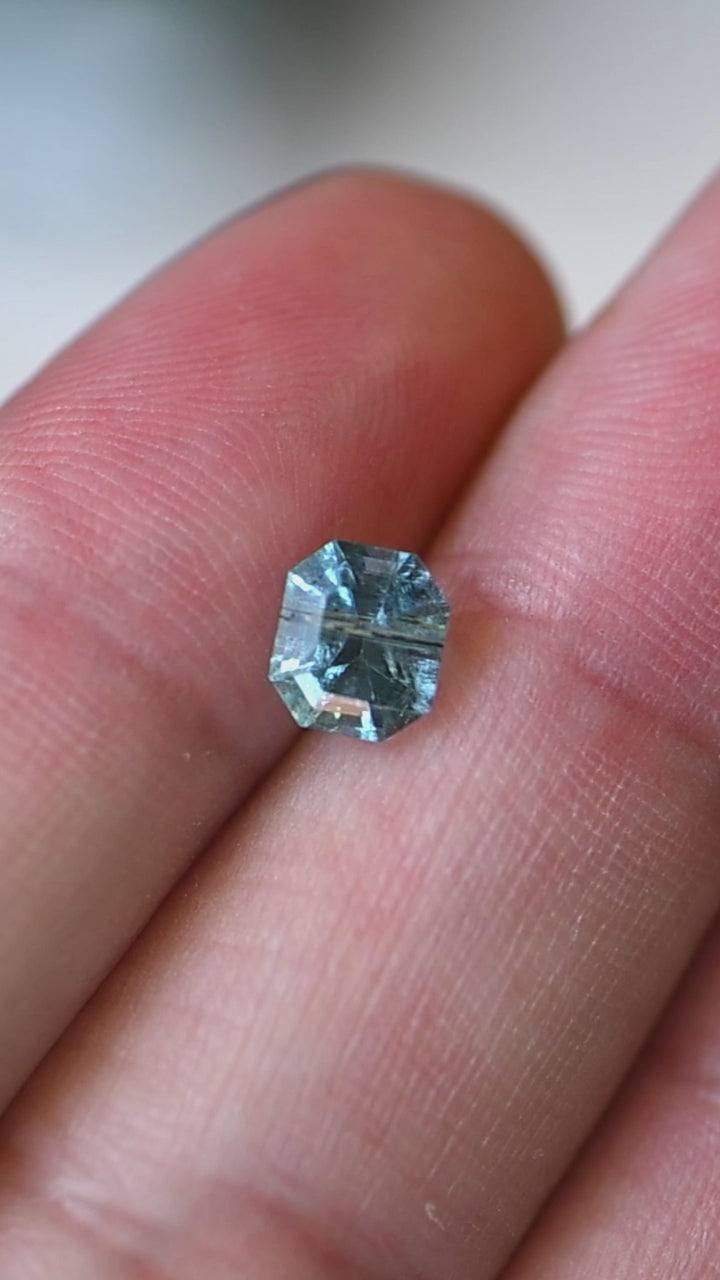 View this untreated 0.88 carat deep teal aquamarine from Nasarawa, Nigeria as it moves through natural light, revealing its precision custom octagonal step cut, vibrant blue-green color, and elegant reflective pattern.