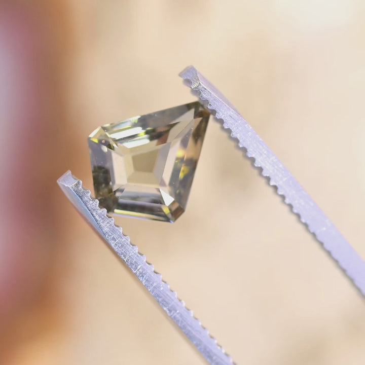 1.72 carat custom kite step cut Tanzanite rotating under light showing golden teal yellow color play and step cut brilliance from Tanzania