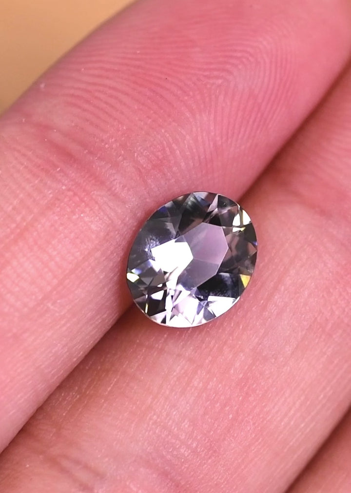 Video of a 2.57 carat natural Tanzanite rotating under light, revealing teal blue and lavender color shifts and brilliant sparkle in a custom modified oval cut, untreated gemstone from Merelani Hills, Tanzania