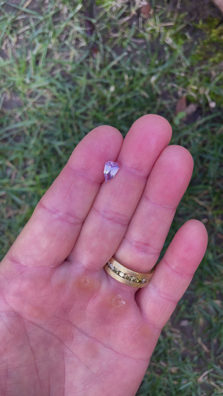 A detailed video of a 1.54-carat geometric shield-cut sapphire, capturing its opalescent pink and purple hues and precise craftsmanship.