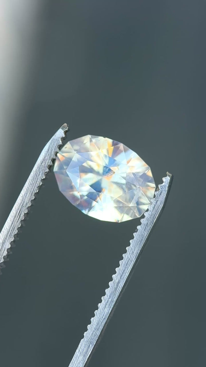 Large opalescent seafoam sapphire rotating in light showing soft glow and shifting off white and green tones.
