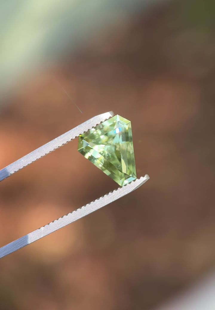 Rotating video of 3.26 carat mint green tourmaline under daylight, showing custom shield step cut brilliance and soft green color transitions, untreated gem sourced from Congo, Africa.